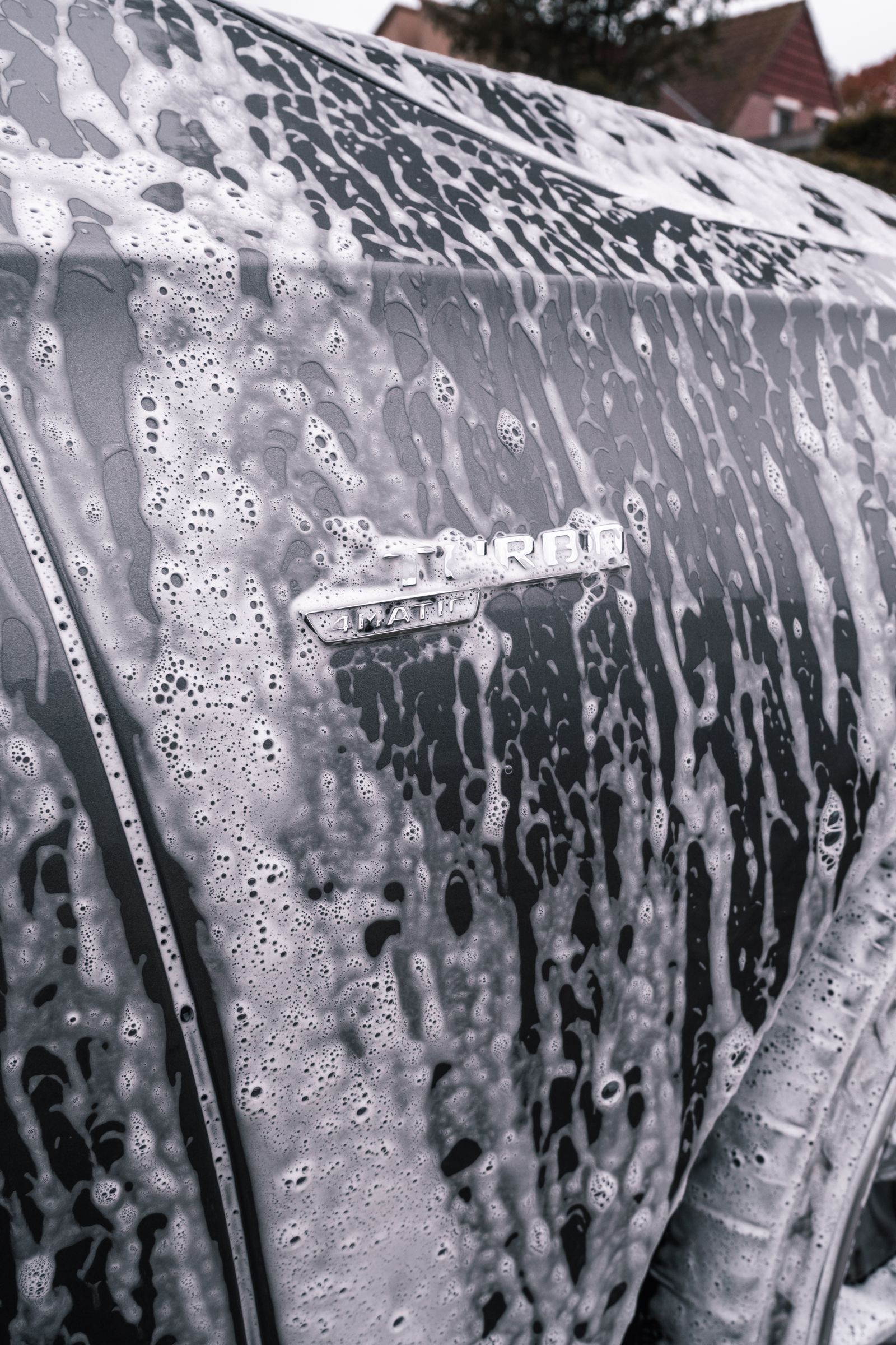 Soap foam on a dark vehicle during exterior cleaning